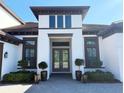 A close up shot of a white two-story home with a beautiful dark wooden door and decorative landscaping at 5305 Brookgrove Dr, Sarasota, FL 34238