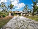 Quaint single-story home featuring a gravel driveway and verdant surroundings under a bright sky at 5645 Churchill Downs Rd, Sarasota, FL 34241