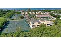 An aerial view of yellow townhouses near tennis courts and with ocean view at 653 Cedars Ct, Longboat Key, FL 34228
