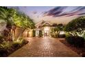 Beautiful home with a brick driveway, lush landscaping, and accent lighting at 11432 Savannah Lakes Dr, Parrish, FL 34219