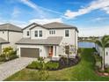 Stunning two-story home featuring a brick driveway, manicured lawn, and view of the lake at 3704 Wild Blossom Pl, Parrish, FL 34219