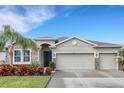 Home exterior showcasing a two-car garage, stone accents, dark front door, and lush landscaping at 452 Tierra Verde Way, Bradenton, FL 34212