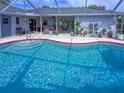 Screened-in pool area with an in-ground pool, patio furniture, and lush landscaping and plant decoration at 9008 Allapata Ln, Venice, FL 34293