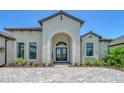 The entryway of this home features a paver walkway, manicured landscaping, and a beautiful arched entryway at 10612 Nicklaus Ct, Englewood, FL 34223