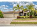 Charming home featuring a stone facade, three-car garage, mature landscaping, and paver driveway at 16621 Berwick Ter, Lakewood Ranch, FL 34202