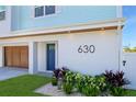Close-up of the home's address (630) with a striking blue door and meticulous landscaping, creating a welcoming entrance at 630 Companion Way, Longboat Key, FL 34228