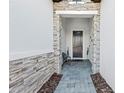 The front door entrance of the house has an elegant exterior design with stone accents and a paved walkway at 328 Aria Dr, Nokomis, FL 34275