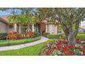 Inviting home entrance with a stone walkway, colorful flower beds, and a beautifully landscaped yard at 2611 Little Country Rd, Parrish, FL 34219