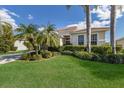 Landscaped front yard with lush green grass, mature bushes, and palm trees framing the home at 6914 45Th E Ter, Bradenton, FL 34203