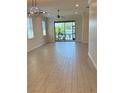 Bright living room with wood-look tile flooring and a sliding glass door leading to a lake view at 204 Villoresi Blvd, Nokomis, FL 34275