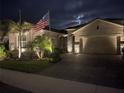 Inviting home exterior at night with an American flag, accent lighting, and a paver driveway at 20296 Bandera Pl, Venice, FL 34293