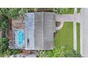 Aerial view of a house featuring a screened-in pool, patio, and brick driveway with lush greenery around the property at 2264 Floyd St, Sarasota, FL 34239