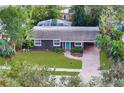 Beautiful house with a brick driveway, vibrant green lawn, and lush landscaping, complemented by a screened-in pool at 2264 Floyd St, Sarasota, FL 34239