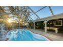 Backyard oasis featuring a sparkling pool, screened enclosure, and covered patio with lounging area at 2264 Floyd St, Sarasota, FL 34239
