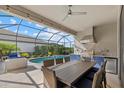 Screened outdoor kitchen featuring stainless steel grill, granite counters, and a stylish ceiling fan overlooking the pool at 2028 Woodleaf Hammock Ct, Bradenton, FL 34211