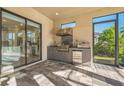 Covered outdoor kitchen features modern stainless steel appliances and sliding glass doors to the interior at 12826 Sorrento Way, Bradenton, FL 34211