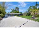 A single story home with a light blue exterior, crushed gravel driveway and partial shade from mature trees at 3902 11Th W Ave, Bradenton, FL 34205