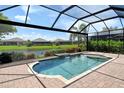 Inviting screened-in pool with waterfall feature, set against a serene lake backdrop with lush landscaping at 4020 Cascina Way, Sarasota, FL 34238