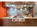 Gourmet kitchen detail featuring a Wolf gas range with stainless steel backsplash and custom wood cabinetry at 7716 Club Ln, Sarasota, FL 34238