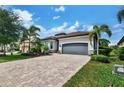 Elegant home featuring a gray roof, paver driveway, and lush landscaping, creating a welcoming curb appeal at 17601 Hickok Belt Loop, Bradenton, FL 34211