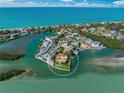 Aerial view of waterfront home with lush landscaping, private dock, and pool on peninsula, surrounded by turquoise water at 929 Casey Cove Dr, Nokomis, FL 34275