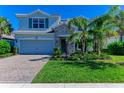 Charming home exterior featuring a stone facade, well-manicured lawn, and a brick driveway, creating a welcoming curb appeal at 3409 Anchor Bay Trl, Lakewood Ranch, FL 34211