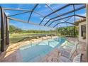 A screened in pool area features a jacuzzi, brick paver flooring and view of tropical landscaping at 3904 Waypoint Ave, Osprey, FL 34229