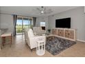 Bright living room with tile flooring, white leather furniture, ceiling fan, and sliding glass doors to the outdoor area at 8402 Grand Estuary Trl # 101, Bradenton, FL 34212