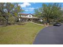 Large home with a spacious front yard, mature trees, and a wraparound porch at 12001 Backwater Rd, Sarasota, FL 34240