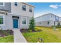 Well-kept home exterior with blue door, beautiful green landscaping, and lush, green lawns at 16606 San Nicola Pl, Lakewood Ranch, FL 34211