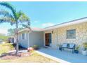 Charming single-story home featuring stone accents, a well manicured lawn, and mature palm trees at 241 Seminole Nw Blvd, Port Charlotte, FL 33952