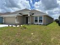 Shows home's exterior, featuring a neutral stucco finish, a two-car garage, and a well-manicured lawn at 2648 Averland Loop, North Port, FL 34287