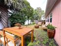 A beautifully landscaped backyard featuring a wooden dining set and seating area, perfect for outdoor entertaining at 1741 Font Ln, Holiday, FL 34691