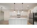Modern kitchen features white cabinets, an island with seating, stainless steel appliances, and designer pendant lighting at 8528 Beechlake Ct, Sarasota, FL 34240