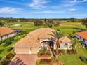 Beautiful aerial view of a home with a terracotta tile roof, two-car garage, and verdant golf course at 124 Ventana Way, Venice, FL 34292
