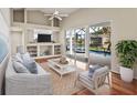 Bright living room with vaulted ceilings, built-in shelves, hardwood floors, and sliding glass doors to the pool at 5383 Creekside Trl, Sarasota, FL 34243
