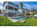 Spacious beachfront home with a large pool, outdoor dining area, and lush green lawn at 915 N Shore Dr, Anna Maria, FL 34216