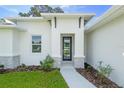 Close up of a modern home featuring a sleek front door, decorative stone accents, and a well-maintained lawn at 1342 Shaker Ln, North Port, FL 34286