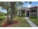 Charming condo exterior featuring a red tile roof, balconies, and mature trees at 3201 Beneva Rd # 204, Sarasota, FL 34232