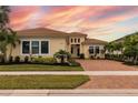 Stunning single-story home featuring a tile roof, lush landscaping, and a brick driveway at sunset at 4839 Pastel Ct, Sarasota, FL 34240