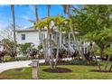 Charming two-story home featuring lush landscaping, a white picket fence, and mature palm trees enhancing its curb appeal at 6821 Longboat S Dr, Longboat Key, FL 34228