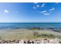 Serene ocean view with clear, shallow water over rocks and sand, under a blue sky with scattered clouds at 7314 Point Of Rocks Rd, Sarasota, FL 34242