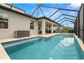 Inviting screened-in pool area featuring travertine tile, blue tile trim, and ample space for outdoor entertaining at 1012 Fernleaf Run, Bradenton, FL 34212