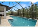The screened-in in-ground pool boasts tile and a sun shelf, with a view of the fenced backyard at 1012 Fernleaf Run, Bradenton, FL 34212