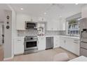 Bright kitchen features white cabinetry, stainless steel appliances, and stylish tile backsplash at 4350 Chatham Dr # 208, Longboat Key, FL 34228