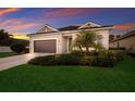 Beautiful one-story home with a lush green lawn, well-manicured landscaping and a sunset sky in the background at 176 Avens Dr, Nokomis, FL 34275