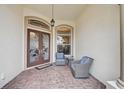 Welcoming front porch with seating area and decorative glass front doors enhancing curb appeal at 1227 Tuscany Blvd, Venice, FL 34292