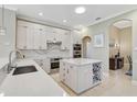 Bright kitchen featuring white cabinets, quartz countertops, modern appliances, and wine storage island at 1227 Tuscany Blvd, Venice, FL 34292
