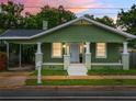 Charming green home with white columns and a cozy front porch enhanced by lush landscaping at 1010 E Lake Ave, Tampa, FL 33605