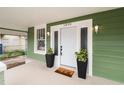Inviting front door with side windows, potted plants, and 'hello' mat on the covered porch at 1010 E Lake Ave, Tampa, FL 33605